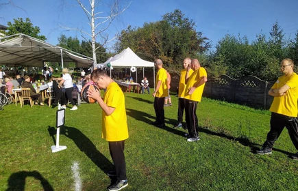 na obrazku tzrech mężczyzn na pierwszym planie w zółtych koszulkach z jednej drużyny jeden trzyma piłkę do koszykówki