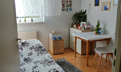 Zdjęcie  przedstawia pokój mieszkańca na którym widzimy wygodne łóżko, stolik i krzesło.