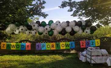 na obrazku balony biało czarne kolorowy napis zawody sportowe 2025 na tle przyrody