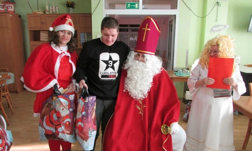 Zdjęcie przedstawia spotkanie z Mikołajem. Na zdjęciu widzimy 4 osoby, w tym Mikołaja, Aniołka, pomocnice Mikołaja i osobę otrzymującą prezent