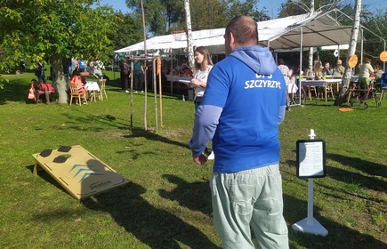 gra w cornhole mężczyzna w niebieskim podkoszulku rzuca woreczkami