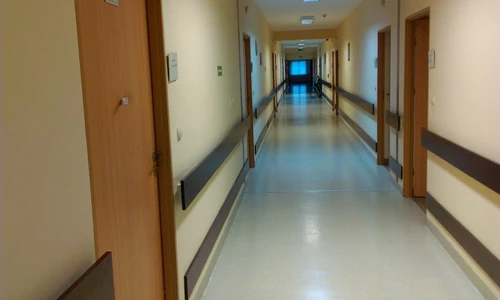 Zdjęcie przedstawia korytarz w którym widać kilka drzwi zarówno po lewej jak i po prawej stronie